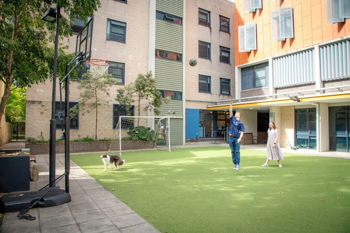 Residents playing basketball with staff family's dog in the courtyard at Robert Menzies College